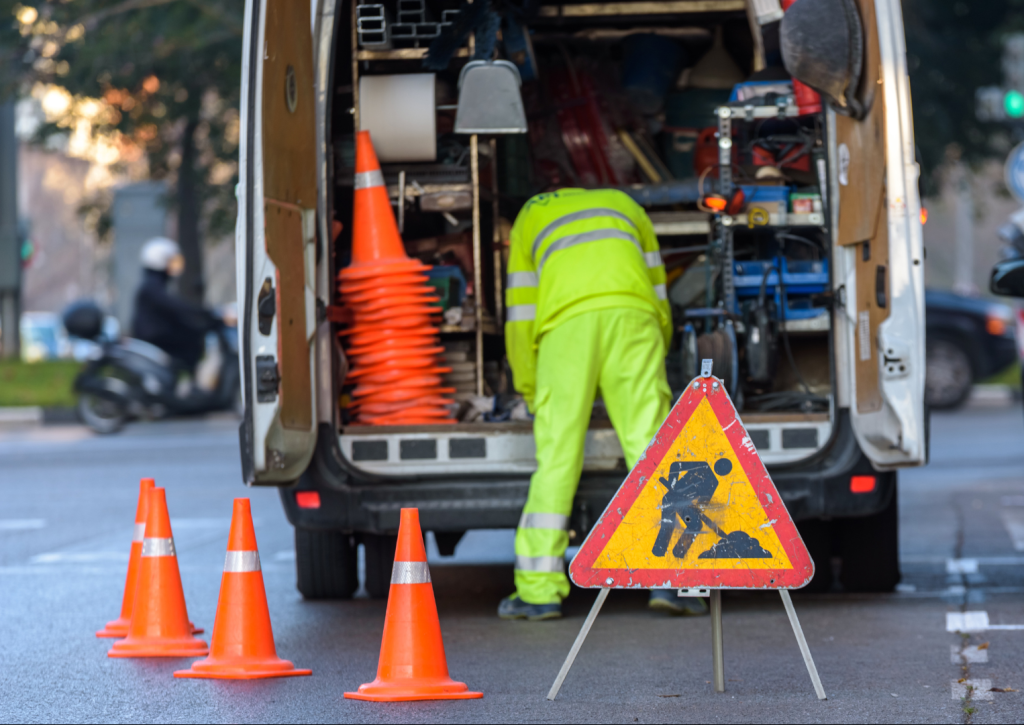 Worker inside his van, loaded with tools, protected from traffic with cones